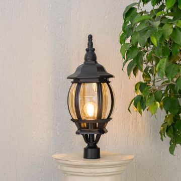 Black metal outdoor pillar light glowing warmly with curved glass panels ideal for driveway garden and patio lighting.