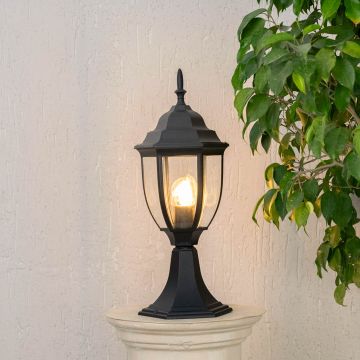 Outdoor black pillar light glowing warmly with LED bulb and clear glass shade suitable for patio garden and balcony use.