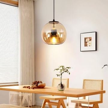 Amber glass pendant light in a cozy dining room with warm glow and wooden dining table and modern home decor.