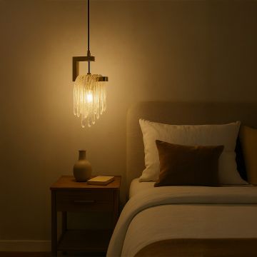 Glass drop pendant light turned on above a bedside table illuminating a cozy modern bedroom with warm ambient glow.