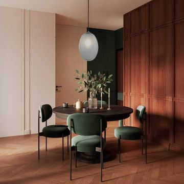 Pendant light with frosted glass shade illuminating a dining space with round wooden table and green chairs.