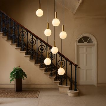 Elegant globe pendant light with bulbs turned on illuminating modern staircase decor with brass accents.