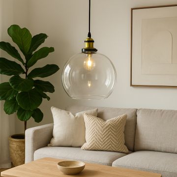 Clear glass globe pendant light with brass holder glowing warmly above beige sofa in modern living room.
