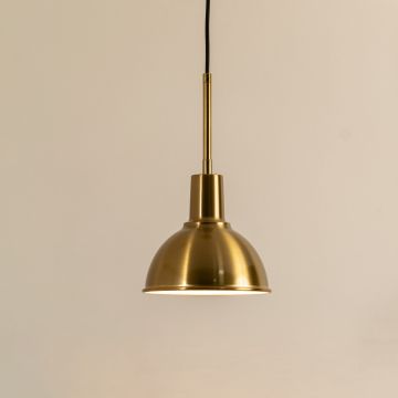 A metal dome pendant light glowing warmly against a neutral beige backdrop offering classic soft illumination and timeless modern interior décor.