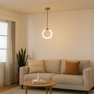 Modern gold pendant light glowing warmly above a cozy beige sofa in a minimalist living room interior decor.