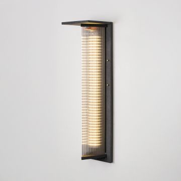Modern outdoor wall light in black metal with ribbed diffuser glowing softly displayed on white background showcasing exterior lighting style.