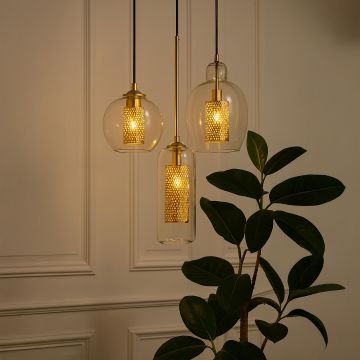 Set of gold and glass pendant lights glowing warmly in elegant living room interior adding luxury and modern ambiance.