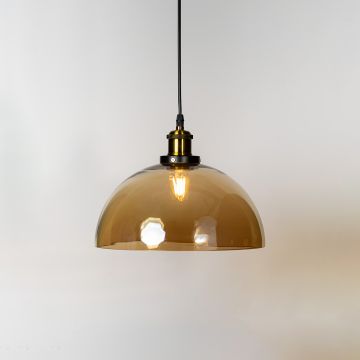 Amber glass dome pendant light glowing on white background with brass and black fitting for stylish interiors.
