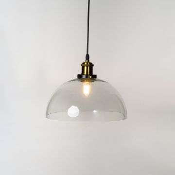 Clear glass dome pendant light glowing on white background with brass and black fitting for interior lighting decor.