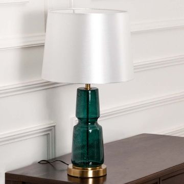 Green glass lamp on bedside table with light off and white wall background for fresh modern décor.