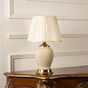 Unlit ceramic table lamp with gold base and pleated shade maintains classic decorative charm and soft neutral elegance even when off.