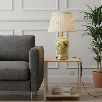 Green ceramic table lamp with hand painted bird and floral artwork brass base and fabric shade styled on bedside table.