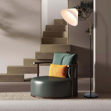 Cozy living room scene with a beige sofa decorative pillows and a stylish floor lamp with a white pleated shade and a gold handle.