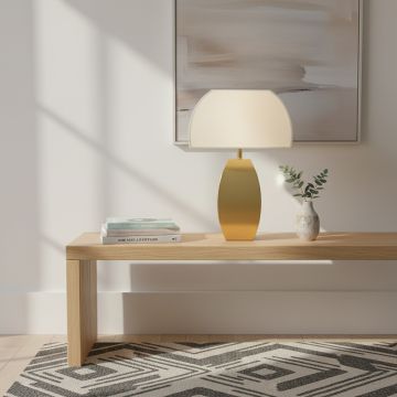 Modern gold metal table lamp with smooth curved base and frosted glass shade styled on bedside or console table.