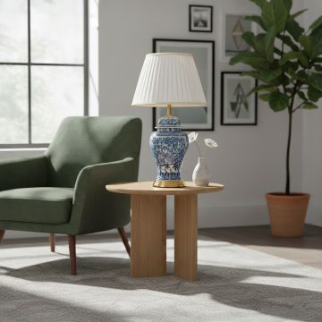 Blue white ceramic table lamp with traditional floral artwork gold metal base and pleated fabric shade styled in living room.