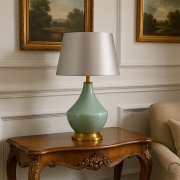 Green table lamp with gold detailing placed on a wooden side table beside the sofa creating a cozy and elegant living room ambiance.