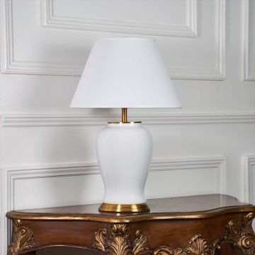 White ceramic table lamp with gold metal base and cone fabric shade illuminated on a white background for elegant home lighting presentation.