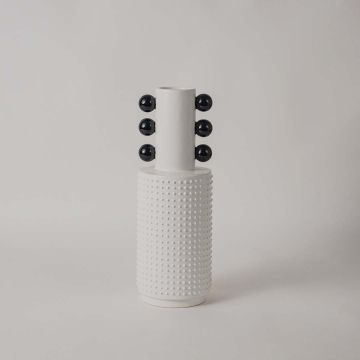 Minimalist white and black ceramic vase with glossy bowl design and ribbed column base on white backdrop.