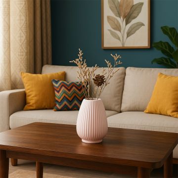 Pink ceramic vase displayed on a wooden coffee table in a cozy living room with mustard pillows and modern wall art.