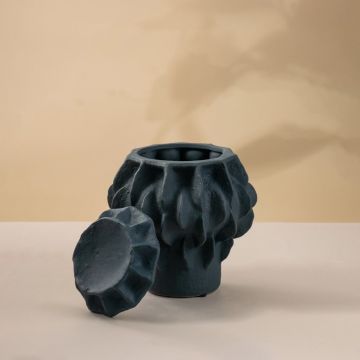 Modern matte black ceramic vase with intricate hand-sculpted detailing placed on white background highlighting its artistic form.