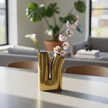 Gold metal double neck vase with glossy finish styled on console table for luxury living room decor accent.