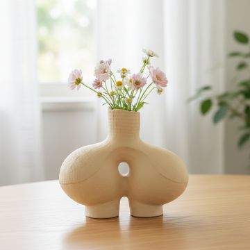 Beige ceramic abstract hollow vase with textured finish styled on console table for modern living room decor.