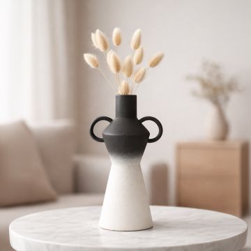 Black and white ceramic sculpted vase with floral stems displayed on table creating bold and artistic interior decor accent.