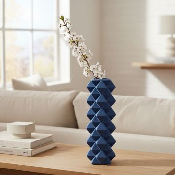 Blue ceramic geometric vase with flowers placed on wooden console table enhancing modern living room decor.