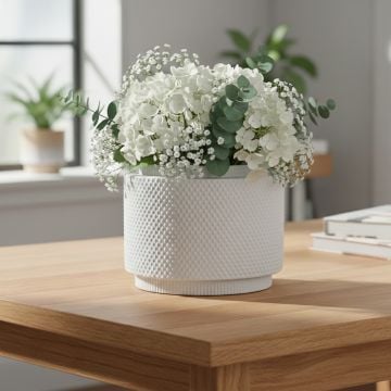 White ceramic planter with green foliage styled on wooden table enhancing fresh and contemporary home decor setting.