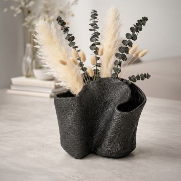 Black textured metal decorative vase styled with dried stems enhancing contemporary home decor setting.