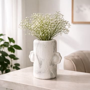 White ceramic sculpted face vase with fresh greenery styled on wooden table enhancing modern artistic home decor setting.