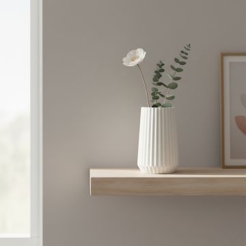 White ceramic ribbed vase with floral stem placed on floating shelf adding clean and modern charm to living room decor.