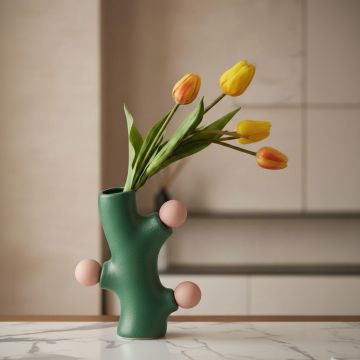 Green ceramic sculpted vase with tulips styled on kitchen counter enhancing bold and contemporary home decor setting.