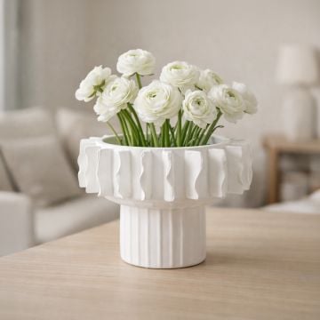 White ceramic frilled decorative vase with white blooms displayed on table creating soft and elegant interior decor accent.