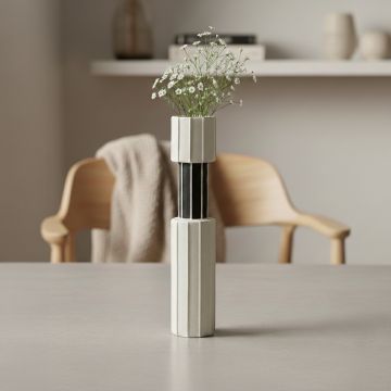 White and black metal decorative vase with floral stems styled on dining table enhancing modern minimalist decor setting.