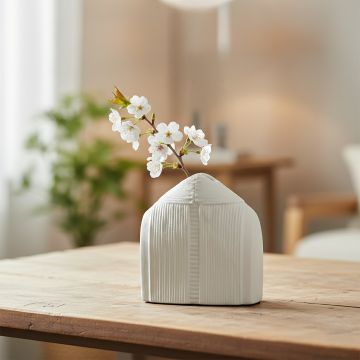 White ceramic dome shaped vase with fresh flowers styled on wooden table enhancing soft minimalist home decor setting.
