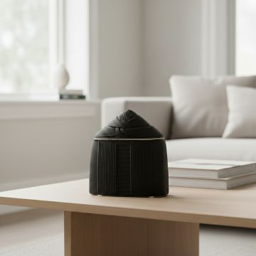 Black ceramic dome shaped decorative vase styled on coffee table enhancing minimalist and contemporary home decor.
