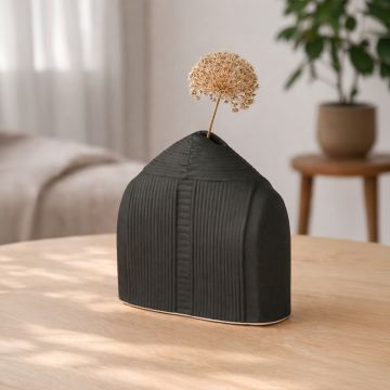 Black ceramic textured decorative vase with dried stem displayed on console creating bold and artistic interior decor accent.