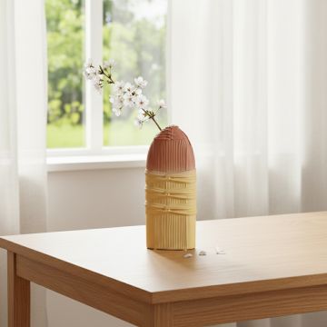 Peach and beige ceramic sculpted decorative vase with floral stem placed on wooden table adding warm modern charm to living room decor.
