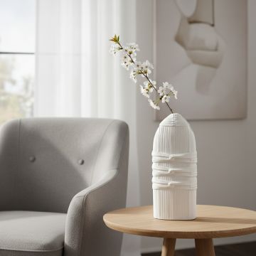 White ceramic sculpted decorative vase with floral stem styled on side table enhancing modern minimalist home decor.