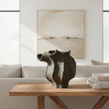Dark green ceramic sculpted vase placed on wooden table adding bold and modern statement to living room decor.
