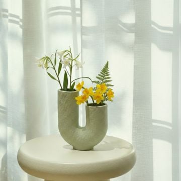 Light green ceramic decorative vase with fresh flowers styled on side table enhancing bright and airy home decor.
