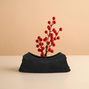 Black ceramic decorative serving bowl with sculpted organic shape perfect for fruit display on dining table centerpiece and modern home decor.