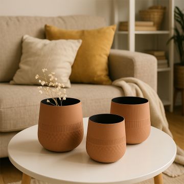 Small terracotta textured pot with black interior styled with matching pots in a warm modern setup creating an earthy decorative look.
