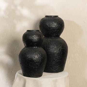 Black textured decorative vase styled in a warm modern room adding bold sculptural decor to living rooms hallways and contemporary interior spaces.