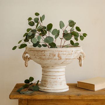 Pedestal bowl styled with green eucalyptus stems on a wooden table for a minimal yet sophisticated home decor look.