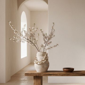 Chain vase with blooming white flowers placed on a wooden table in an airy neutral hallway for elegant home decor styling.