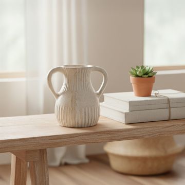 Double handle vase styled on a wooden bench beside books and a small succulent in a bright minimal living room.