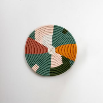 Handwoven multicolor wall plate in green mustard peach and cream tones on a white background showcasing detailed craft and smooth coil design.