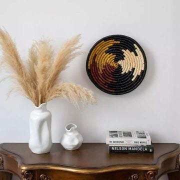 Woven plate used as wall decoration in a modern dining area with rustic wooden furniture and soft lighting ambiance.